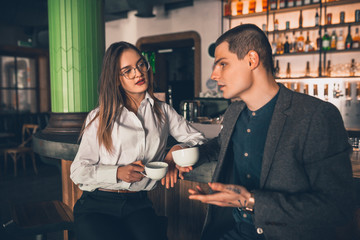 Cheerful caucasian man and woman talking, enjoying at the coffee shop, cafe, bar. Couple or friends, business partners drinking toghether, having a date, romantic. Communication, relations concept.