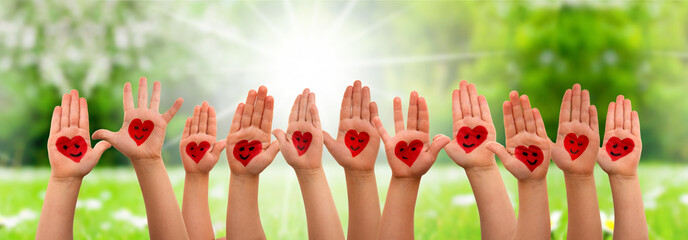 Many Children Hands Showing Red Heart Symbols And Smileys. Grass Meadow As Background