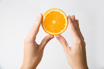 Female hands showing cut half of orange fruit isolated on white background. Cropped shot, closeup. Healthy nutrition or organic food concept