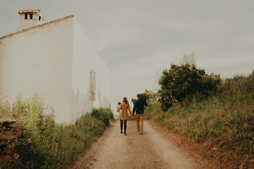 Young couple walking hand in hand by a path, and woman carrying their baby in the arm.