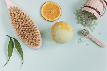 On an blue background are care products: a bomb and sea salt for the bath and body brush. For aromatherapy: orange slices. The concept of home Spa.
