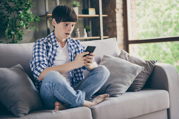 Obraz premium Oh no. Photo of teenager school boy sit comfy couch staying home quarantine time hold telephone hands read teacher email distance online many tasks homework open mouth living room indoors