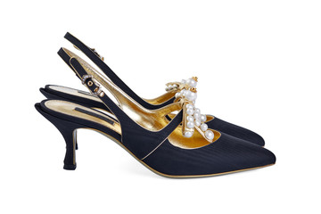 Pair of women's open shoes made of black fabric on the outside and gold leather on the inside, decorated with pearls on a small thin stiletto heel, isolated on a white background. Side view.
