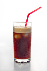 Glass with cold ice coffee and red straw on white background