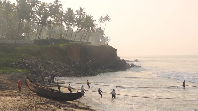 Local people working with traditional fishing nets, Kappil Beach, Varkala, India, at dusk