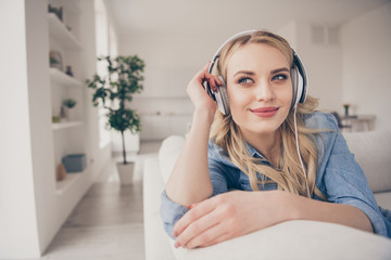 Naklejka premium Photo of domestic charming blond lady miss going outdoors sit comfy couch staying home listen cool earphones youth music dreamer look window quarantine time living room indoors
