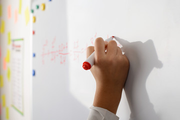 Hand of a young learner on the board writing some math eguation. Concept of math lesson in secondary school