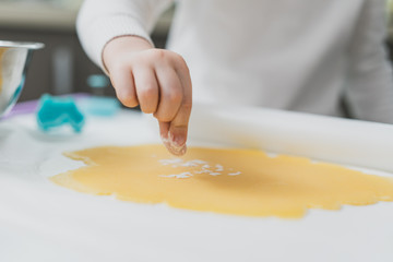 Perfect shortcrust pastry on the surface, a child's hand sprinkles it with flour, making cookies