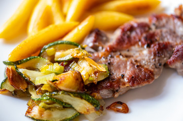 Pork neck steak with vegetable and french fries.