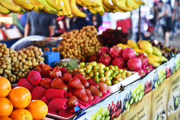 A fruit market with oranges, longan, bananas, dragon fruit, mangoes, mangosteen, limes and apples.