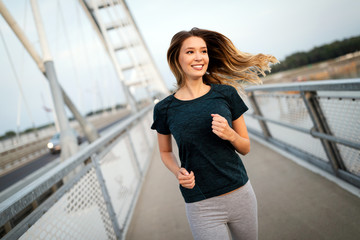 Beautiful fit happy runner woman crossing bridge