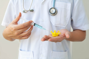 Coronavirus vaccine. Closeup of doctor injecting vaccine into coronavirus model. Concept of medical research for coronavirus vaccine. Prevention and treatment of coronavirus infection. Selective focus