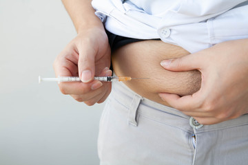 Obese diabetes man injecting insulin into his belly. Subcutaneous injection technique, Selective focus.
