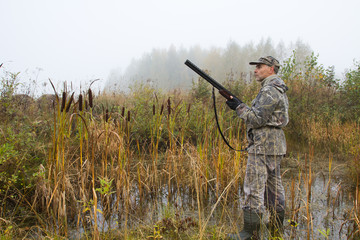 Fototapeta premium the hunter stood at the edge of the swamp with his shotgun ready