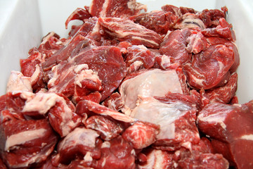 A worker at the meat processing factory, prepares sausages at the work table. Food processing and processing industry. Raw meat mix: steaks, poultry, sausages, ham, chopped, minced meat. The farm