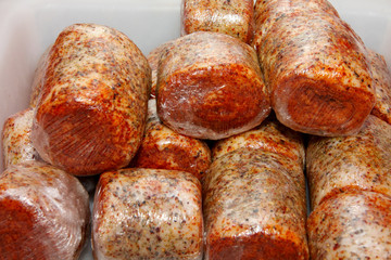 A worker at the meat processing factory, prepares sausages at the work table. Food processing and processing industry. Raw meat mix: steaks, poultry, sausages, ham, chopped, minced meat. The farm