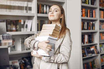 Girl in the library. Student looking for a book. Lady in a brown coat.