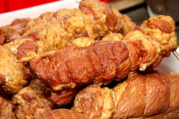 A worker at the meat processing factory, prepares sausages at the work table. Food processing and processing industry. Raw meat mix: steaks, poultry, sausages, ham, chopped, minced meat. The farm