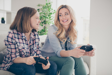 Photo of funny blond lady mom daughter sitting comfy couch hold joystick play video game teamwork stay home quarantine spend weekend together best friends living room indoors