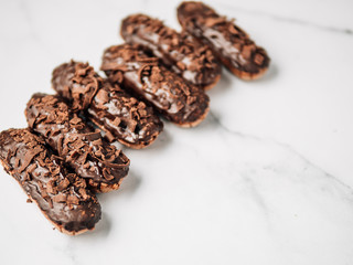 Set of homemade eclairs with chocolate on marble background. Close up view of delicious healthy profitroles with chocolate glaze. Copy space for text or design