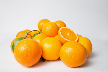 Pile of orange fruits with green leaves isolated on white background. Closeup shot. Natural vitamin or organic food concept