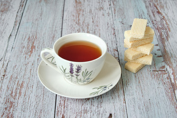 Top view of a mug with red tea and wafer biscuits on wooden table