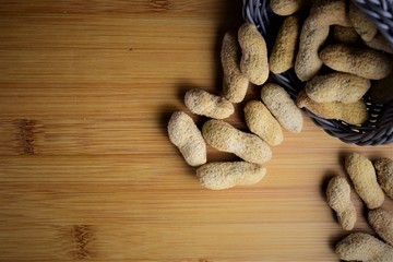 Peanuts, on a wooden board grouped together, small basket
