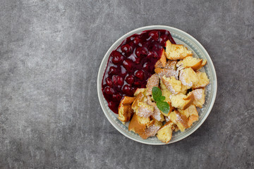 Kaiserschmarren or Kaiserschmarrn is a traditional Austrian or German sweet pancake dessert, with icing sugar and berry, cherry sauce or rote grutze jam. Top view. Copy space.