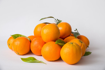 Heap of whole oranges with green leaves isolated on white background. Side view. Natural vitamin or organic food concept