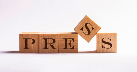 Five wooden cube blocks with the text press on a newspaper background