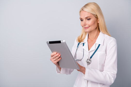 Portrait of focused retired pensioner woman doc use tablet search corona virus medication pneumonia treatment wear white coat isolated over gray color background - Powered by Adobe