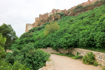 Walls and towers of old medieval Sagunto impregnable fortress ruin on a hill in Spain surrounded by green forest