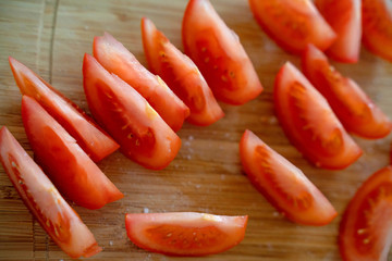 Sliced tomato with salt on the cutting board background