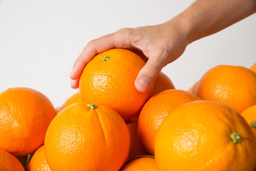 Hand of unrecognizable person taking orange from fruits pile isolated on white background. Cropped shot, side view. Healthy nutrition or organic food concept