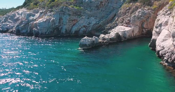 Forward aerial shot of a seagull sitting on some rocks next to the sea, Greece. 4K video quality