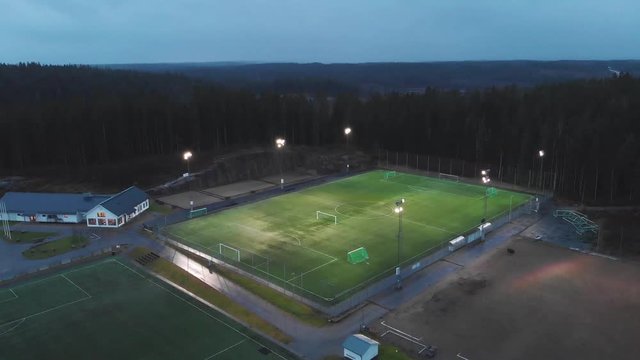 A football pitch lit up in the evening.