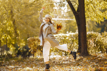Fototapeta premium Girl in a brown coat. Woman in a autumn park. Lady with a leaf.
