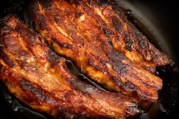 Juicy fried pork ribs in a cast iron pan