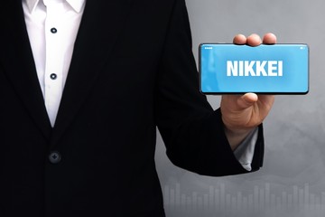 NIKKEI. Geschäftsmann im Anzug hält ein Smartphone in die Kamera. Der Begriff NIKKEI steht auf dem Handy. Konzept für Business, Finanzen, Statistik, Analyse, Wirtschaft