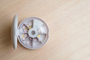 pills in a medicine container with cells by day of the week on a wooden table copy space. medicines, medicines and vitamins for health