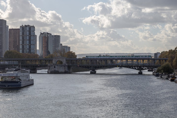 Subway train crossing over Seine river in urban Paris France on cloudy but sunny day
