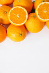 Pile of whole and sliced orange fruits isolated on white background. Closeup, vertical shot, top view, copy space. Natural vitamin or organic food concept