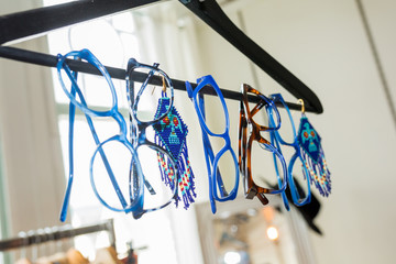Blue glasses hangin on a clothing rack with decoration in between. 