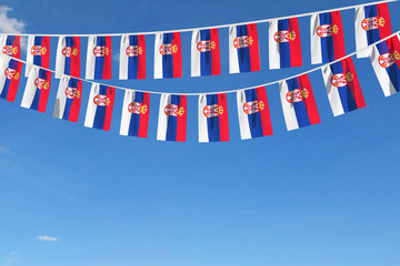 Serbia flag festive bunting hanging against a blue sky. 3D Render