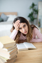 Sad young woman with books sit at work desk.