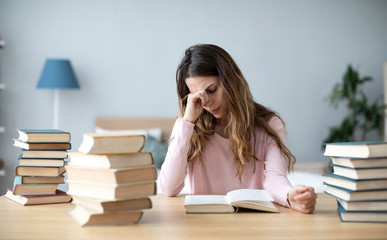 Sad young woman with books sit at work desk.