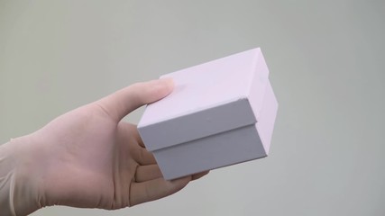 Male Hands in protective latex gloves give  white gift box.