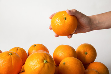 Unrecognizable person taking orange from pile of fruits isolated on white background. Cropped shot, side view. Healthy nutrition or organic food concept