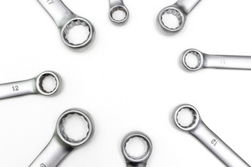 Chrome ring spanners of various sizes are laid out in a circle. Isolated on a white background.