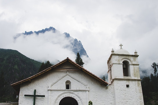 Iglesia con monta&ntilde;as y nubes al fondo en un pueblo 